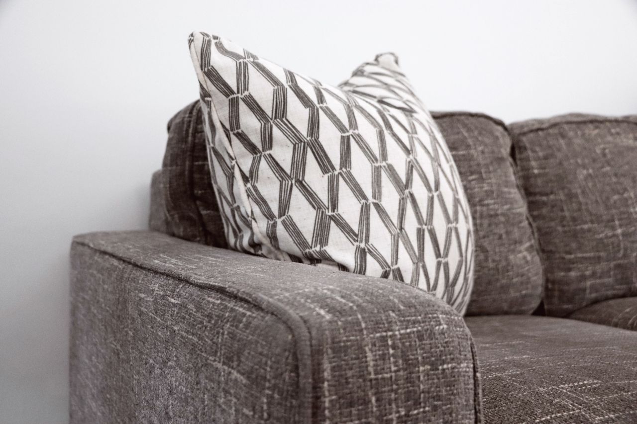 Stylish gray sofa with a patterned throw pillow adds elegance to any living space.